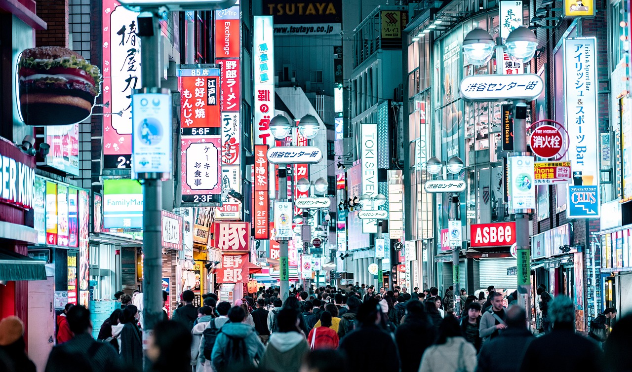 A busy shopping street in Tokyo lit by store signs at night