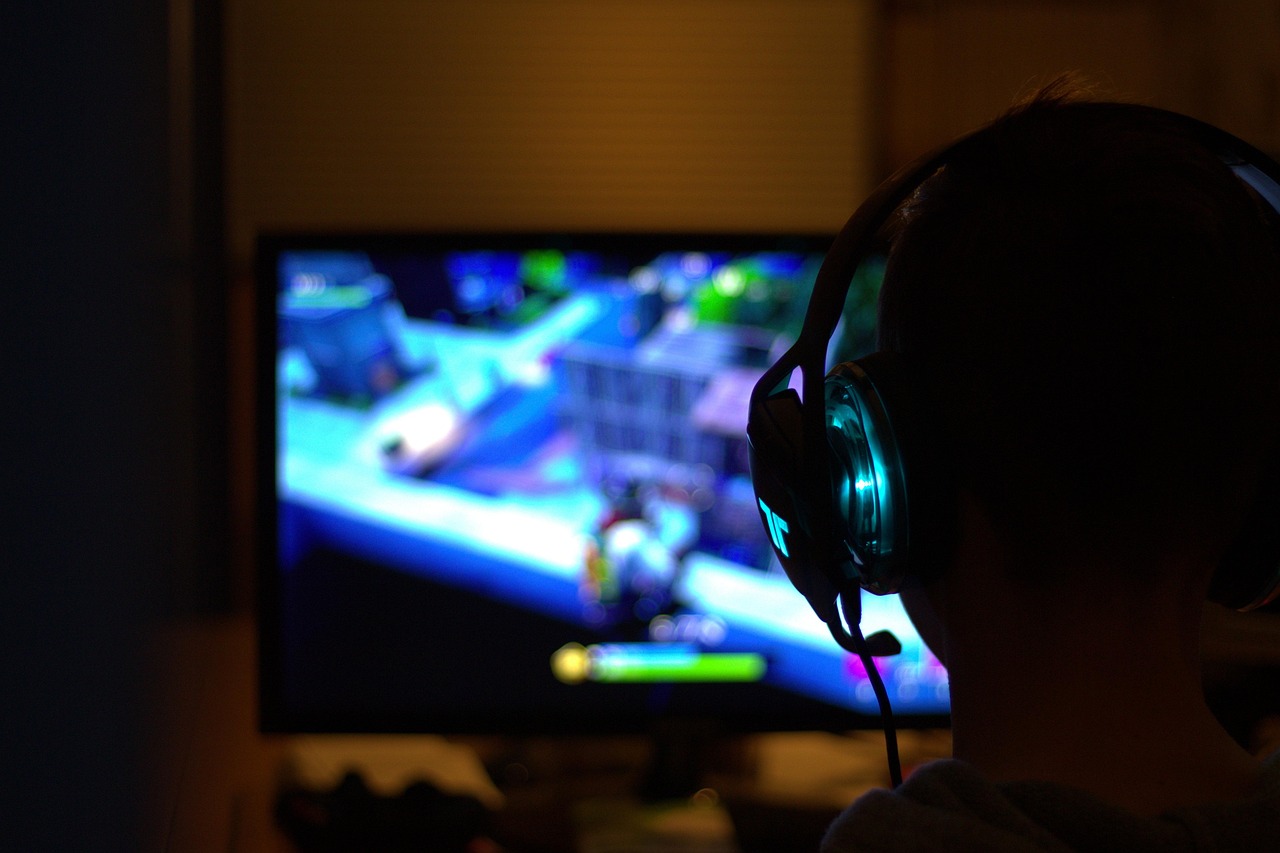 A gamer with a headset playing in front of a monitor