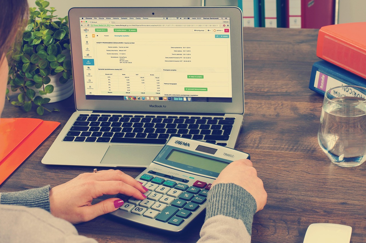 Working on an invoice with a laptop and calculator