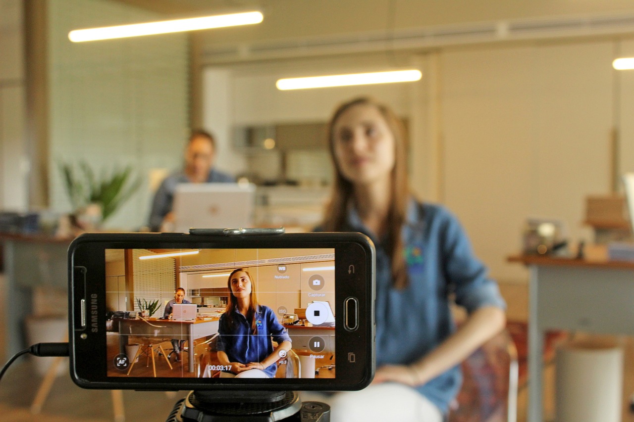 A woman being filmed on a smartphone in a studio