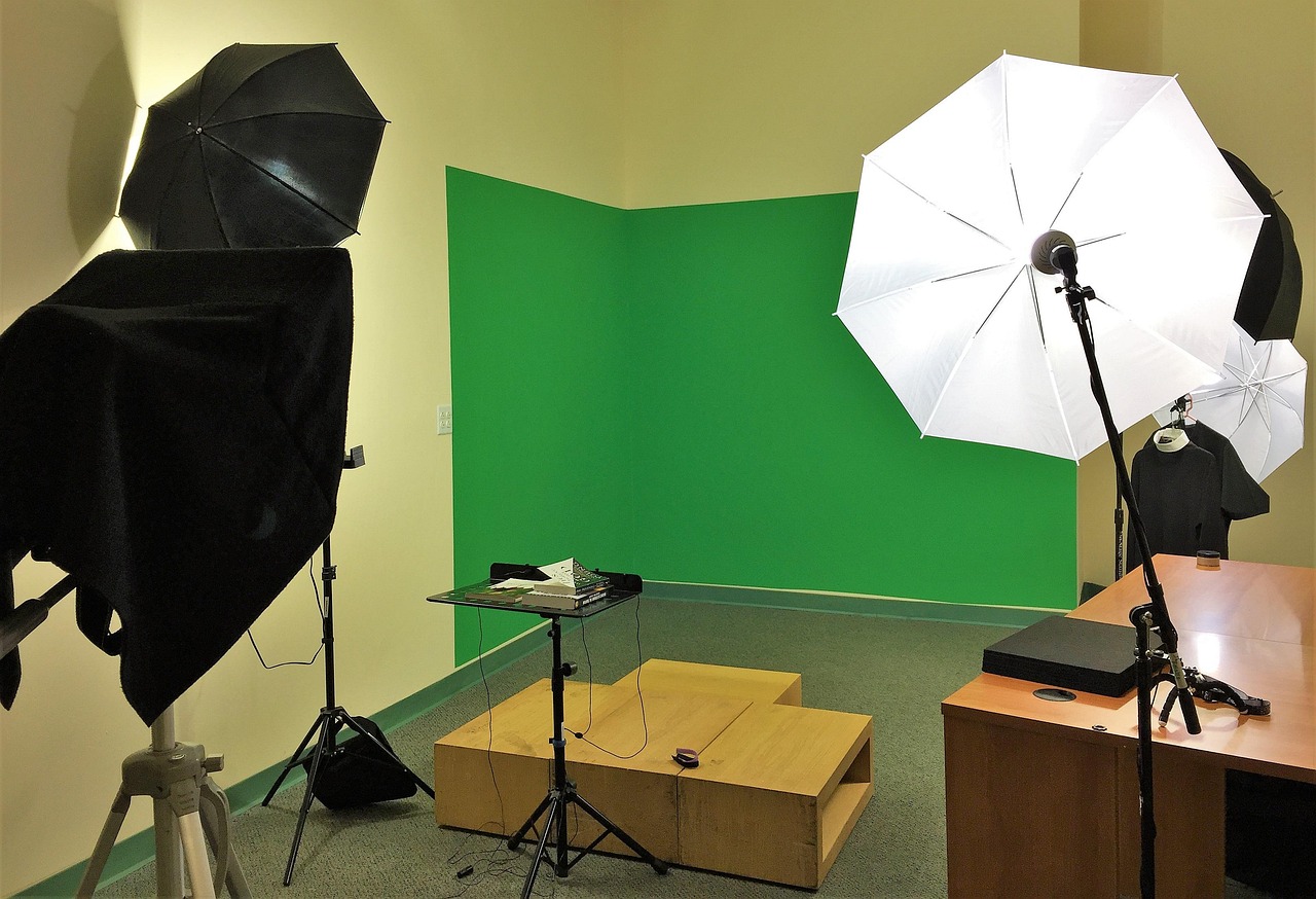 A small studio set up with lights and a green screen for filming