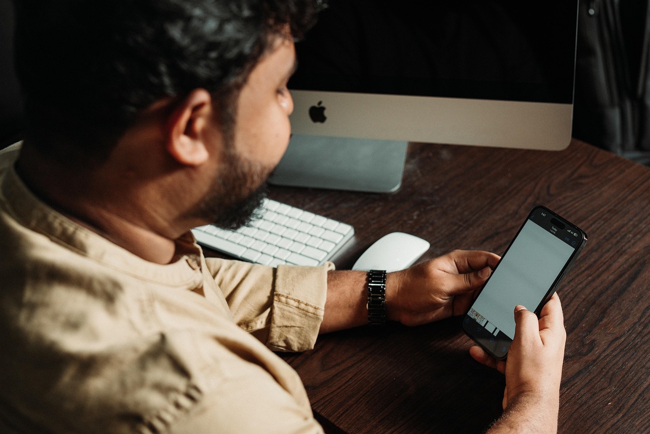 A marketer checking a smartphone at a desk